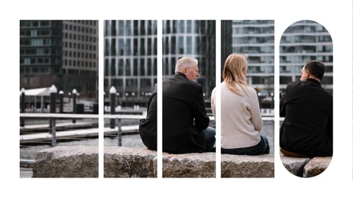 Three people seated outside of an office building, having a conversation.
