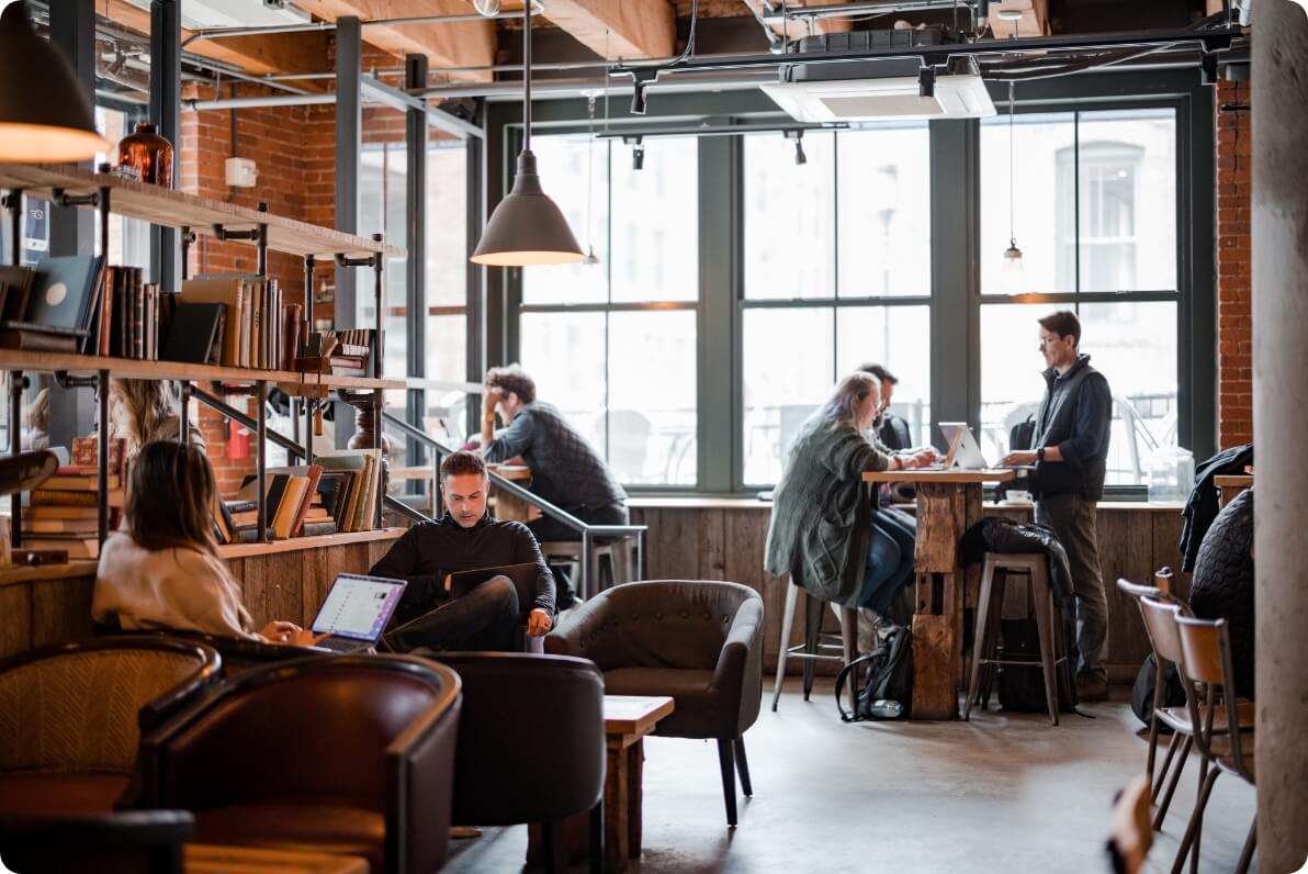 Employees working in small pods or individually at a cafe.