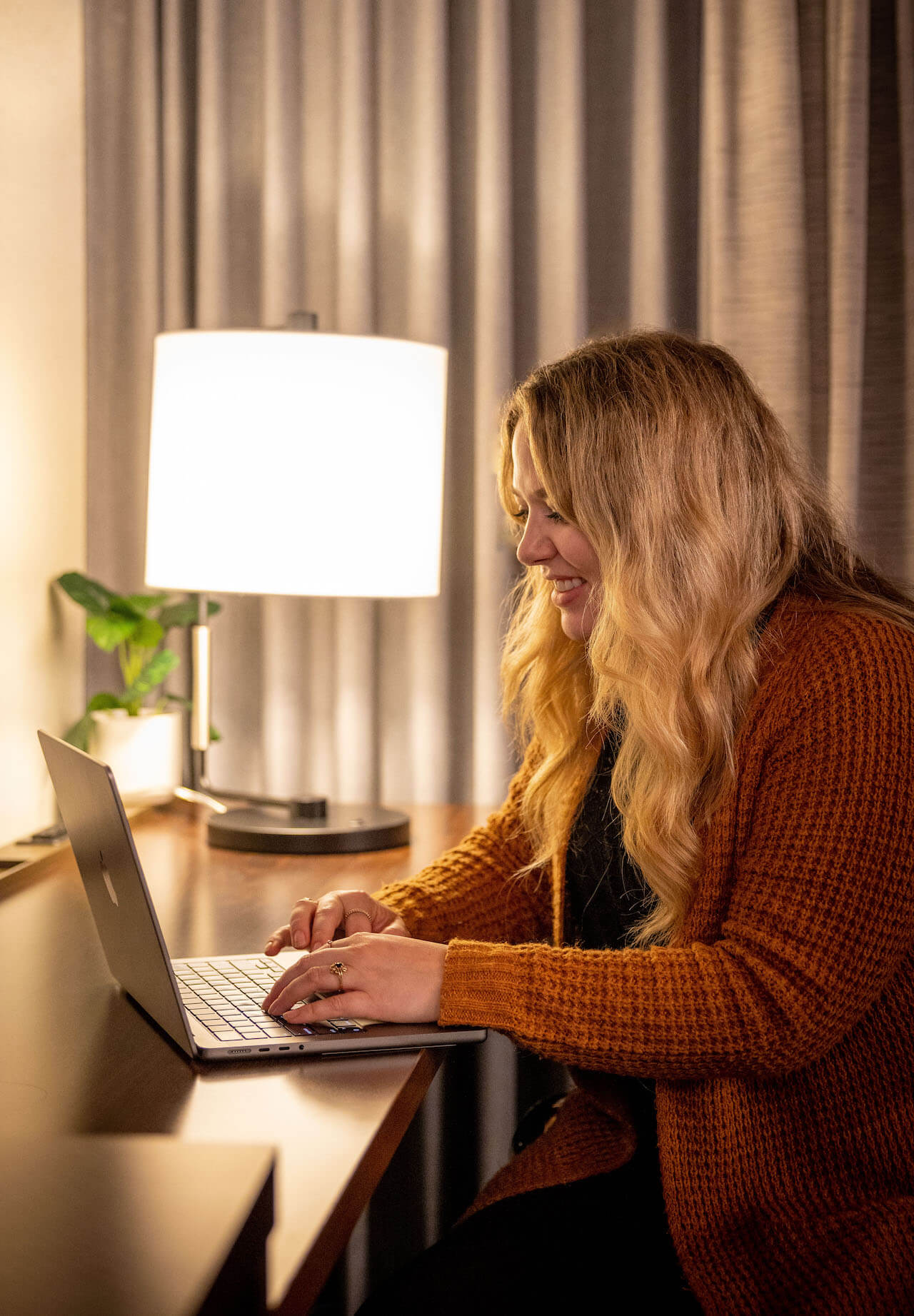 An employee in her hotel room working on her laptop.