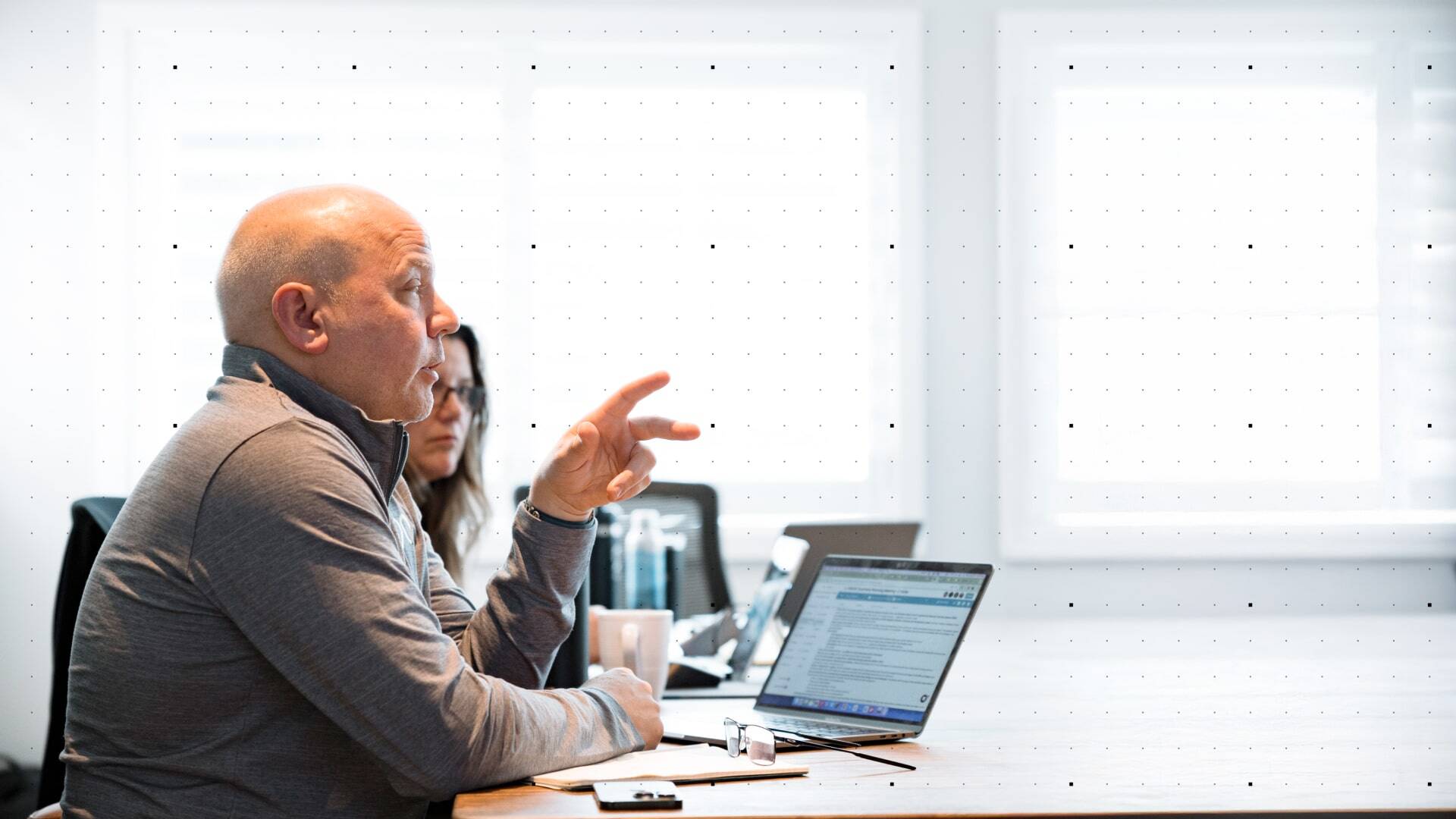 Team discussing the annual plan in a modern office setting, with laptops and documents on the table.